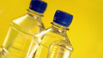 wo plastic bottles of water against a yellow backdrop, illustrating food contact migration testing