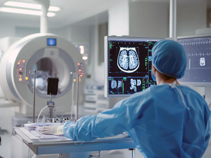 A medical technician calibrating an imaging device in a hospital room, with medical equipment and screens around
